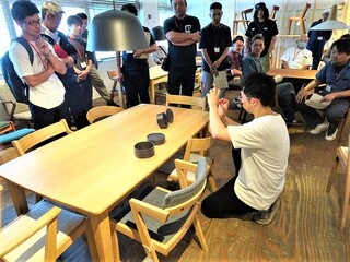 展示している木製家具の説明を受けている参加者